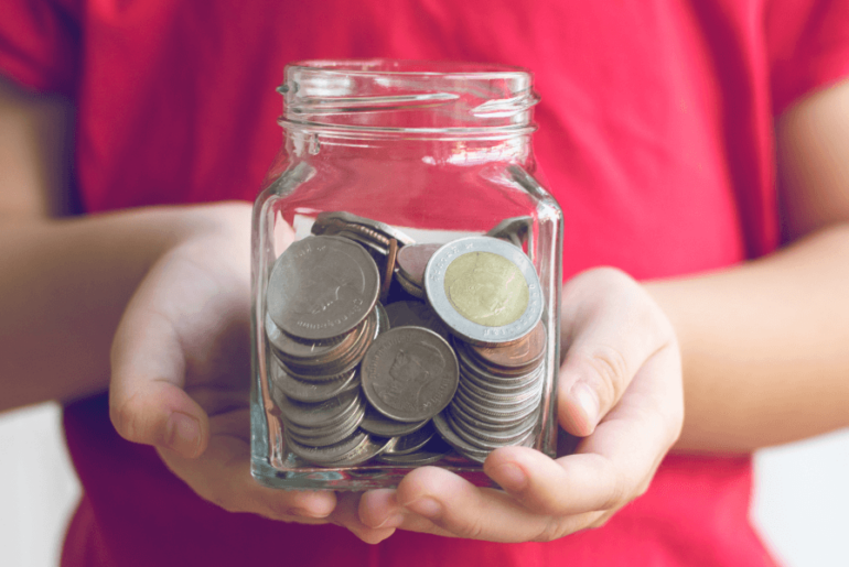 Niño sosteniendo una taza de vidrio con dinero