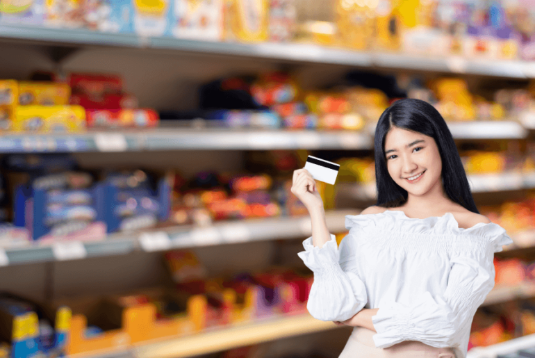 Mujer con una tarjeta frente a los pasillos de los supermercados - Tarjeta EBT