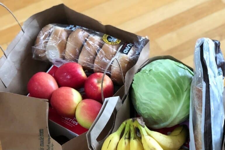 bolsas de comestibles con manzanas, plátanos, bagels y lechuga - Compras