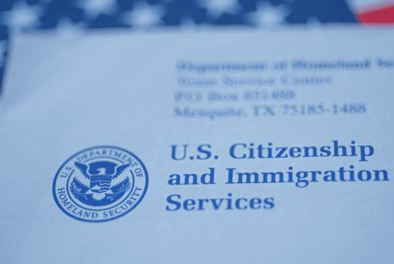 Sobre de USCIS con la bandera estadounidense atrás - Advance Parole