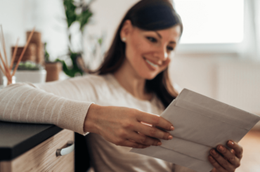 Mujer alegre revisando el correo recibido en casa, concéntrese en un correo -Ayuda económica en 2022
