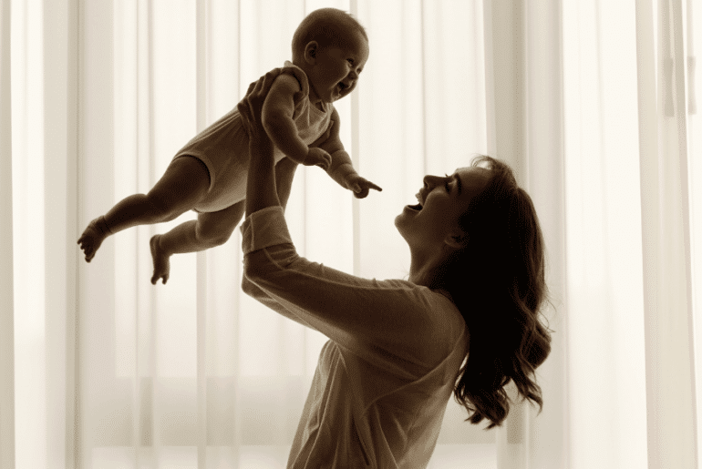 Madre sonriente con bebé en sus brazos - Ayuda para madres solteras en EE.UU.